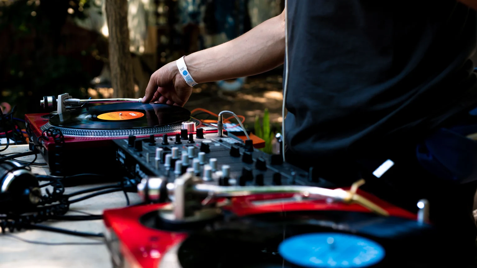 DJ am Plattenspieler in einer grünen Outdoor-Location